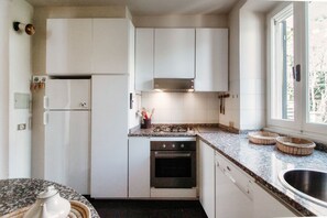 A kitchen with white cabinets, a stove, an oven, and a window.