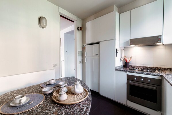 A modern kitchen with white cabinets, a granite countertop, a built-in oven, and a stainless steel range hood.