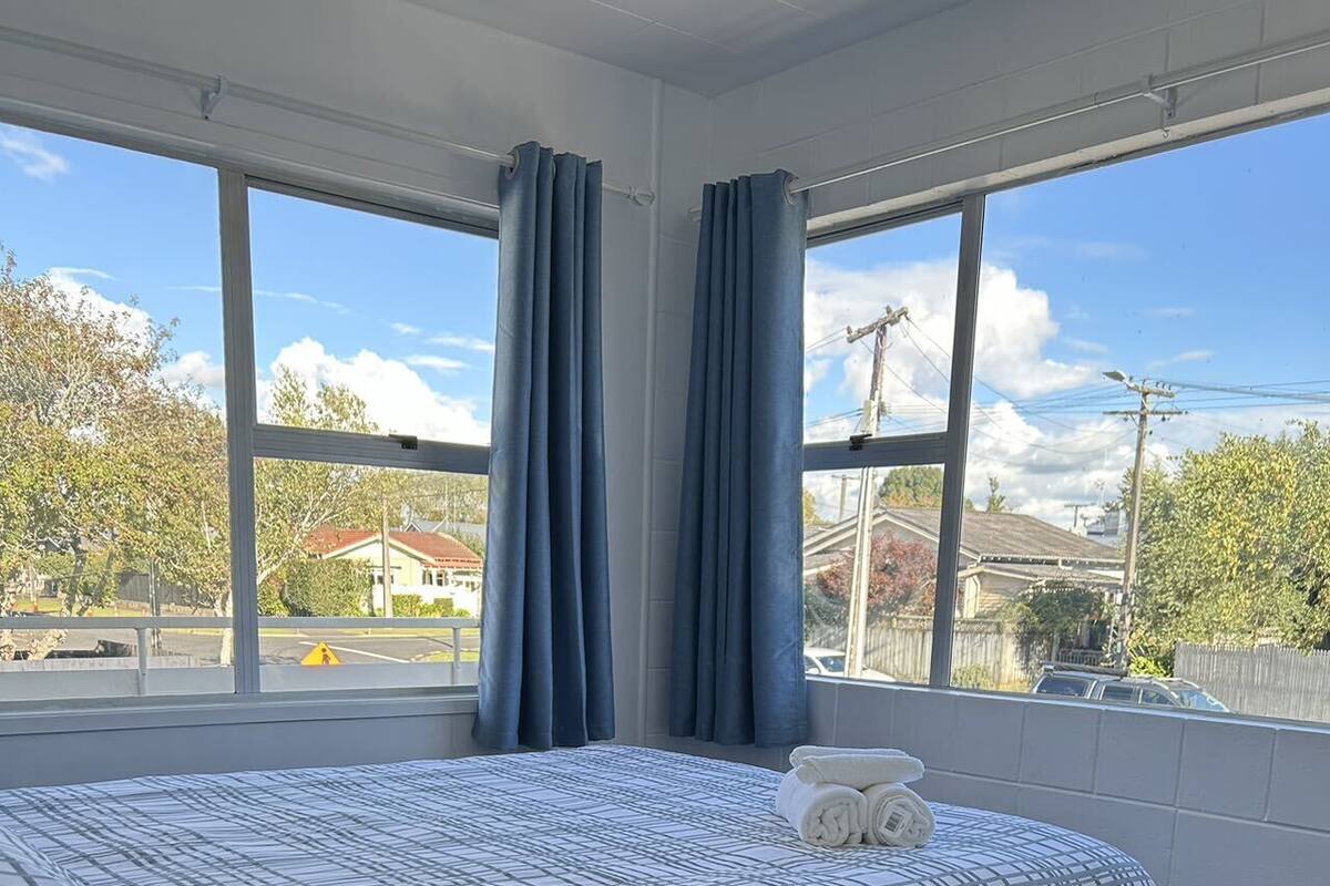 A hotel room with a large bed, a view of the outside, and a window with curtains.
