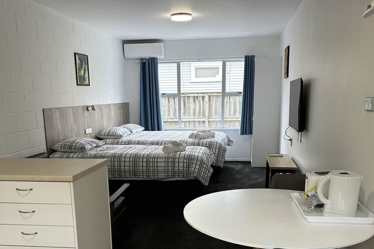 A compact hotel room with a bed, a desk, a chair, and a small table.