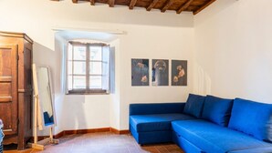 A room with a wooden ceiling, a blue sofa, a wooden cabinet, and a window.