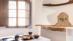 A kitchen with a window, a brick oven, and breakfast items on the counter.