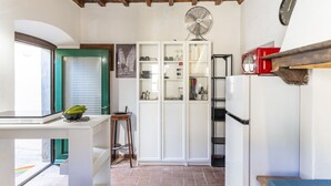 A kitchen with a fan, a refrigerator, and a window with blinds.