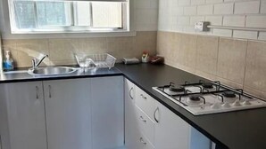 A kitchen with white cabinets, a black countertop, a gas stove, and a window above the sink.