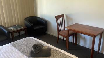 Une chambre d’hôtel avec un lit, un bureau, une chaise et un tableau accroché au mur.