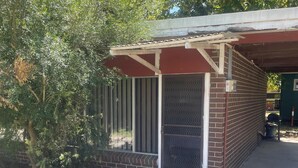 A small, single-story building with a brick exterior and a covered porch area. - CABIN 2Q - Couple or single, motel style cabin (Thornton)