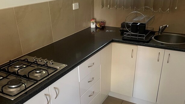 A kitchen with a gas stove, a sink, and white cabinets. - CABIN 2Q - Couple or single, motel style cabin (Thornton)