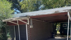 A single-story building with a covered garage and a fenced area. - CABIN 2Q - Couple or single, motel style cabin (Thornton)