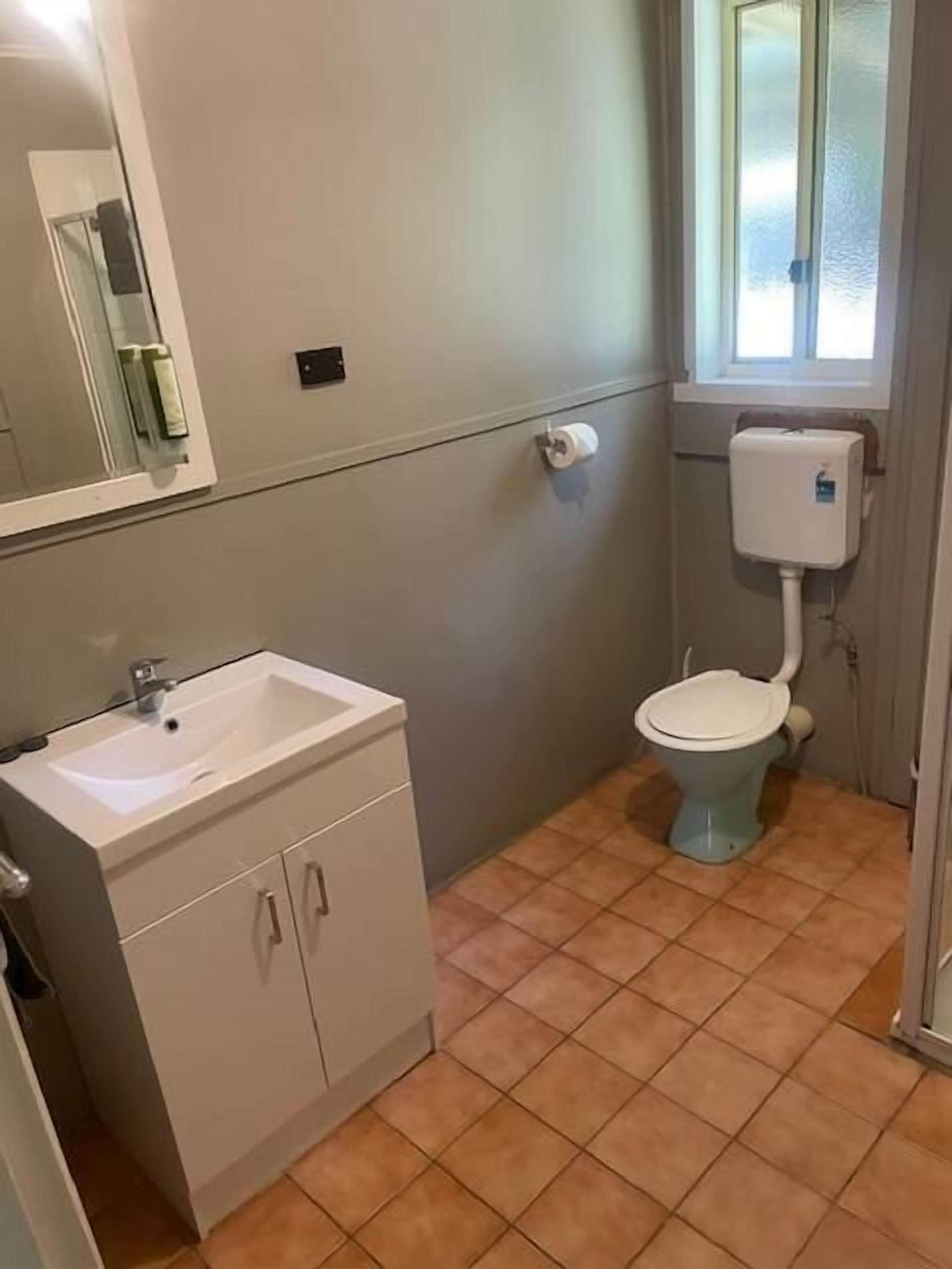 A bathroom with a white sink, a toilet, and a window.