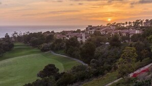 Un campo de golf con vista a un pueblo costero y al océano al atardecer.