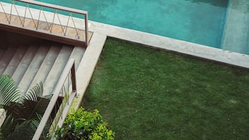A rectangular swimming pool with a wooden deck and a grassy area.