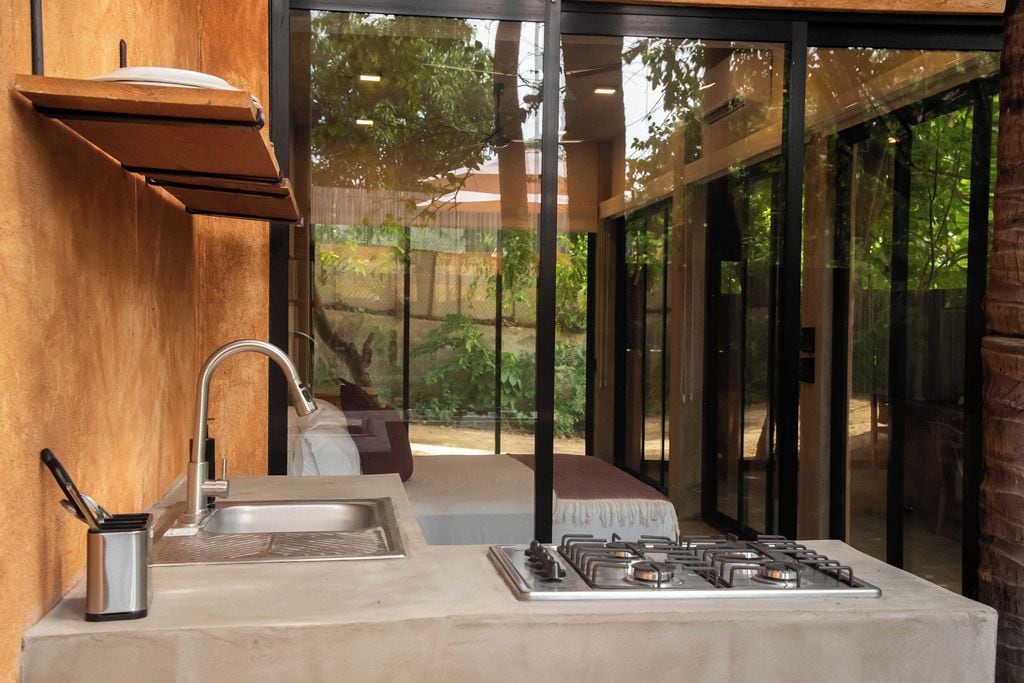 A kitchen with a sink, stove, and a view through large glass doors.
