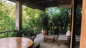 A covered outdoor seating area with a table, chairs, and a potted plant.