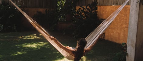 Un hamac dans un jardin, avec une clôture en bois et de la verdure.