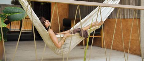 A hammock in a modern room with a concrete floor and wooden furniture.