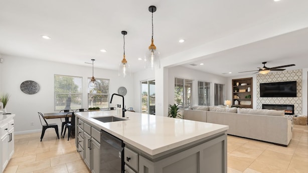 Een ruime keuken met een groot eiland, hanglampen en een moderne uitstraling.