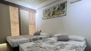 Ett hotellrum med två sängar, en stor, abstrakt målning och en luftkonditioneringsanläggning.