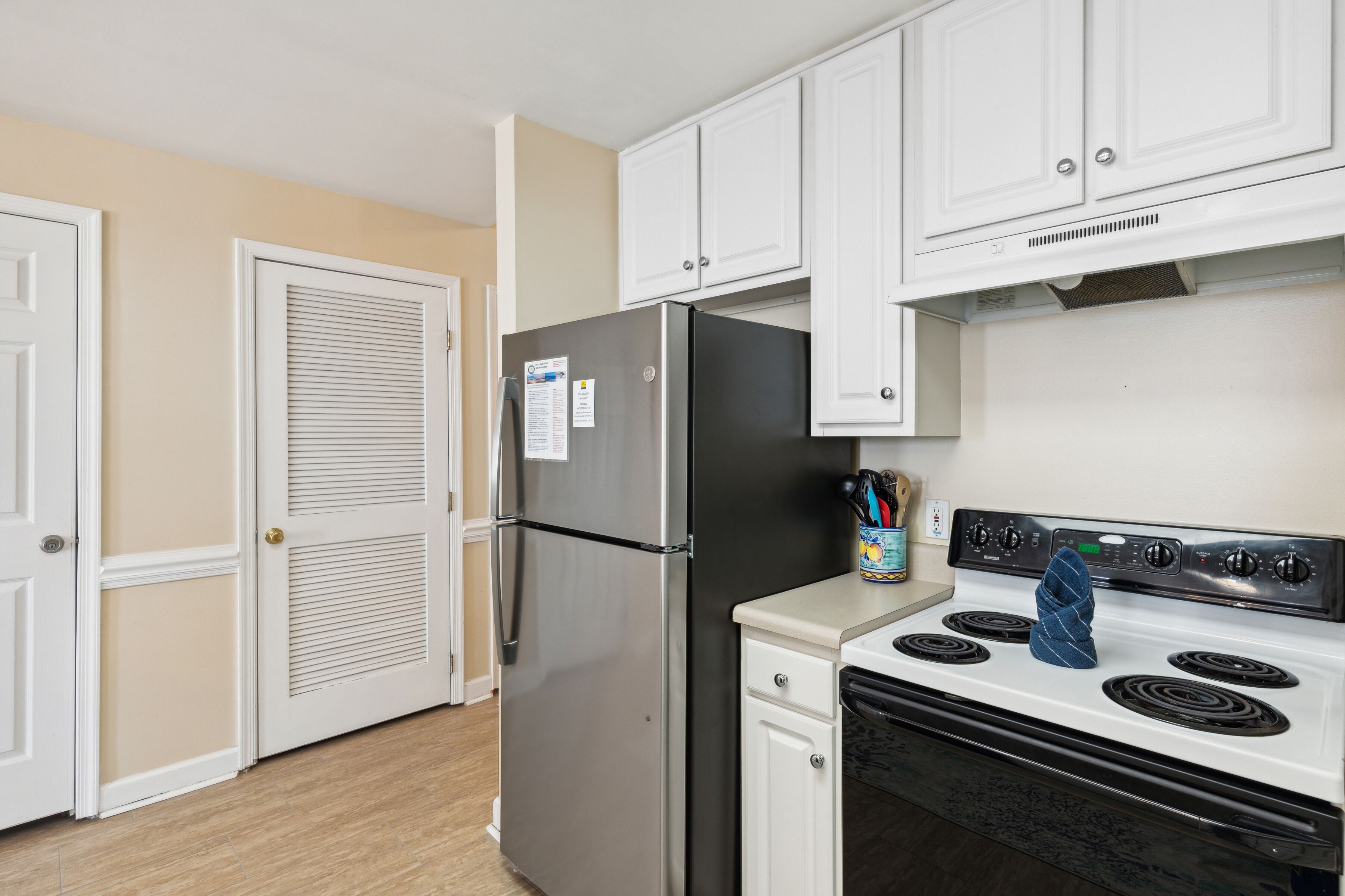 A kitchen with white cabinets, a stainless steel refrigerator, a stove, and a microwave.