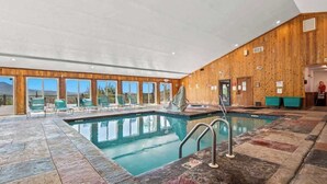 Une piscine intérieure avec un mur en bois et de grandes fenêtres.