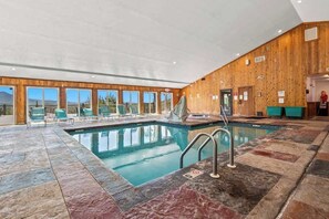 Une piscine intérieure avec un mur en bois et de grandes fenêtres.
