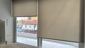 Een slaapkamer met een bed, een aan de muur bevestigde televisie en een raam met uitzicht op een blauwe balustrade.