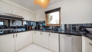 A modern kitchen with white cabinets, black countertops, and stainless steel appliances. - Pet Friendly - TJ's Tree House with Ocean Views (Cape Schanck)