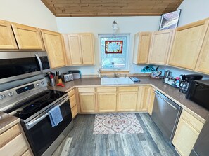 Une cuisine moderne avec des meubles en bois, des appareils en acier inoxydable, une fenêtre ornée de vitraux et un tapis à motifs.