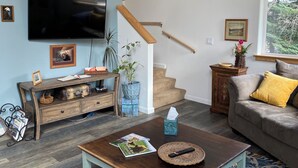 Un soggiorno con televisione, mobili in legno, una scala e una finestra con vista.