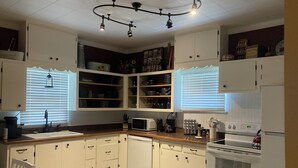 A compact kitchen with white cabinets, a microwave, a stove, and a sink. - Blocks from downtown and has that country feel. Nestle in Columbia Falls comfort (Columbia Falls)