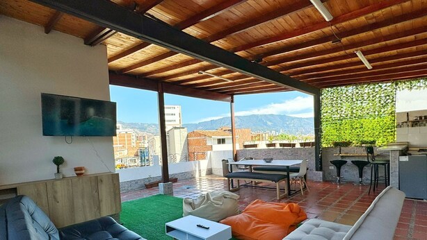 A rooftop terrace with a dining area, seating, and a TV. - Compostela Estadio (Medellín)