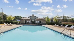 A swimming pool with lounge chairs and a building in the background. - Serene Spring Retreat (Bloomington)