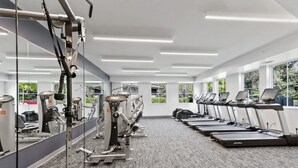 A gym with cardio machines, weight machines, and a mirrored wall. - Serene Spring Retreat (Bloomington)
