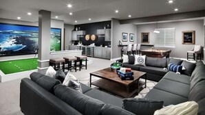 A modern living room with a large flat-screen TV, a sofa, a coffee table, and a pool table. - Serene Spring Retreat (Bloomington)