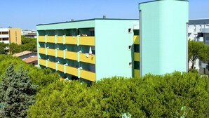 A multi-story building with a distinctive yellow and green color scheme, featuring a curved section on the right side. - Calm Apartment Perfect for up to 4 Guests (San Michele al Tagliamento)