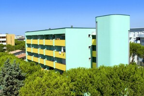 A multi-story building with a distinctive yellow and green color scheme, surrounded by greenery. - Calm Apartment Perfect for up to 4 Guests (San Michele al Tagliamento)