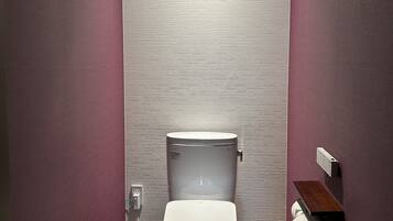 A modern bathroom with a white toilet, a small framed picture on the wall, and a wooden floor.