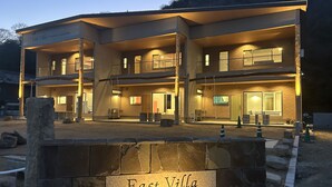 Un edificio de varios pisos con base de piedra, con la leyenda "East Villa Shimanami Mukaishima".