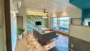 Una sala de estar moderna con un sofá, un televisor de pantalla plana y un ventanal con vistas al mar.