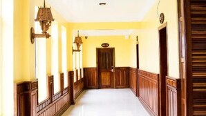 A hallway with wooden paneling, a white floor, and a door at the end. - Puok hotel & Resort (Puok)