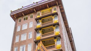 A multi-story building with a traditional Thai architectural style, featuring ornate golden decorations and multiple balconies. - Puok hotel & Resort (Puok)