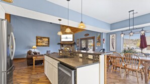 Una cocina con lavavajillas integrado, un comedor con sillas de madera y una pared de acento de piedra.