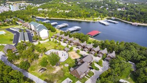 Vista aérea de una zona residencial junto al lago, con casas, un puerto deportivo y un edificio grande con techo verde.