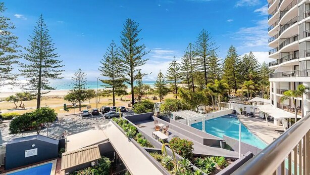 A resort with a pool, beach view, and multiple balconies.