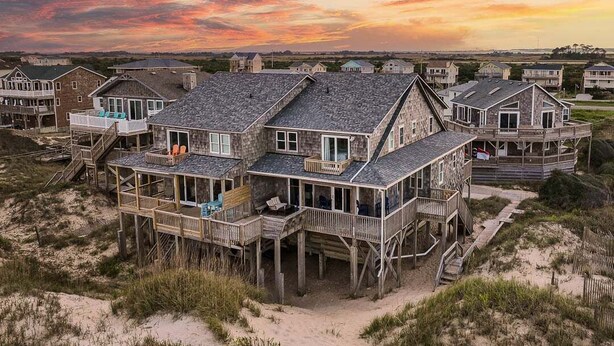 Ein Strandhaus mit mehreren Terrassen und einer sandigen Umgebung.