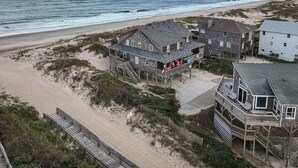 Ein Strandgrundstück mit mehreren Häusern, darunter ein großes Haus mit Balkon und ein kleineres Haus mit Terrasse.