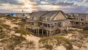 Ein Strandhaus mit mehreren Ebenen, einer Holzterrasse und Blick auf den Ozean.