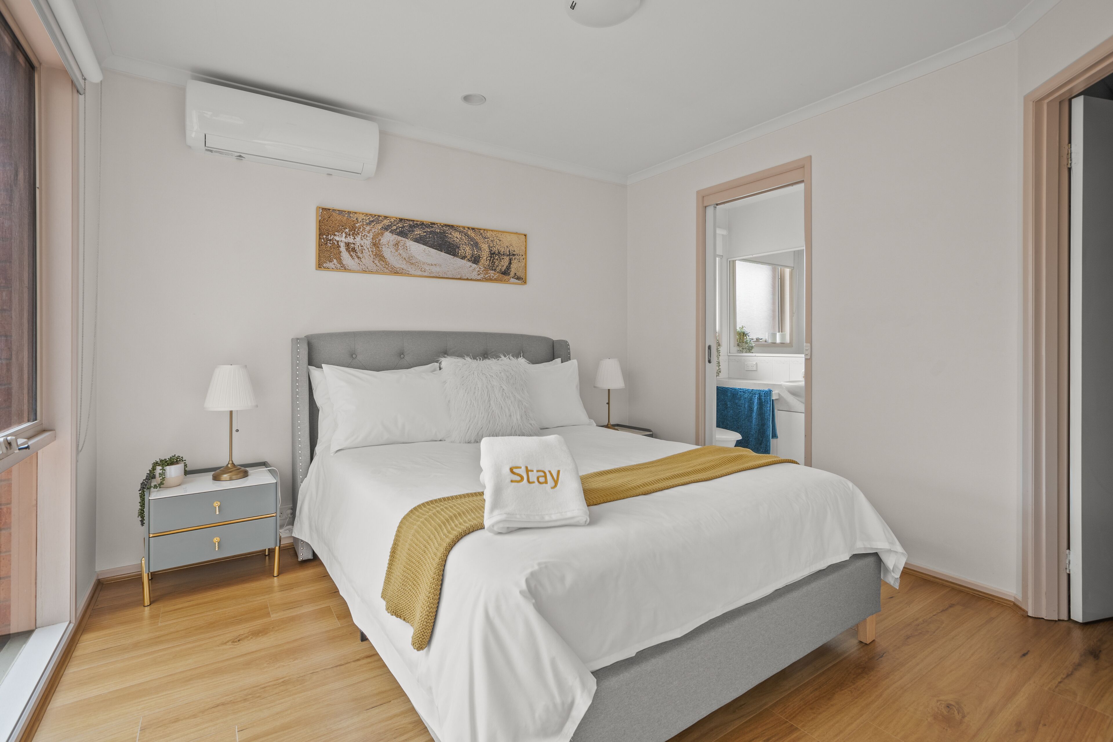 Une chambre à coucher bien rangée, avec un lit, des tables de chevet et un tableau accroché au mur.