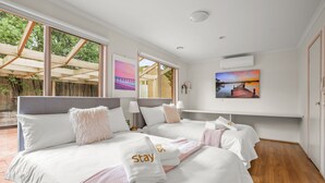 Ett hotellrum med två sängar, stora fönster, konstverk på väggarna och utsikt över omgivningarna.