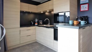 Une cuisine moderne avec des meubles en bois, un plan de travail noir et un four encastré.