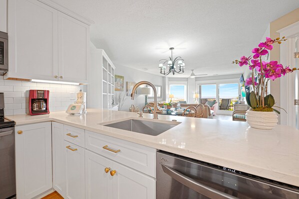 A modern kitchen with white cabinetry, a stainless steel dishwasher, and a double sink.